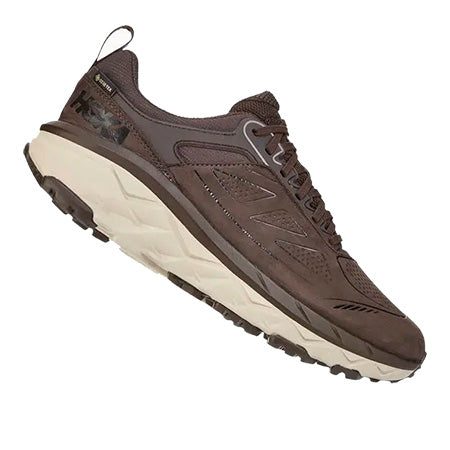 A brown athletic shoe with a thick, off-white sole and black details on the heel and tongue, designed for all-terrain traction. The Hoka HOKA CHALLANGER LOW GORE-TEX BROWN - MENS model excels as a trail runner.