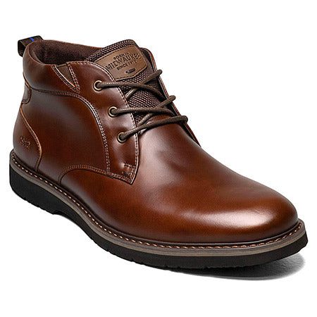 The NUNN BUSH DENALI CHUKKA BROWN - MENS by Nunn Bush is a brown leather lace-up ankle boot with a rubber sole, featuring a sleek design and visible stitching along the edges. It boasts waterproof leather upper and includes a Memory Foam insole for ultimate comfort.