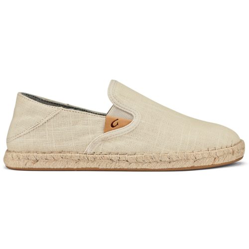 A side view of a light beige women’s shoe, the Olukai Olukai Kaula Pa'a Kapa Tapa/Tapa - Womens, featuring a woven straw sole, a small leather patch near the opening, and Drop-In Heel® design for versatile wear.