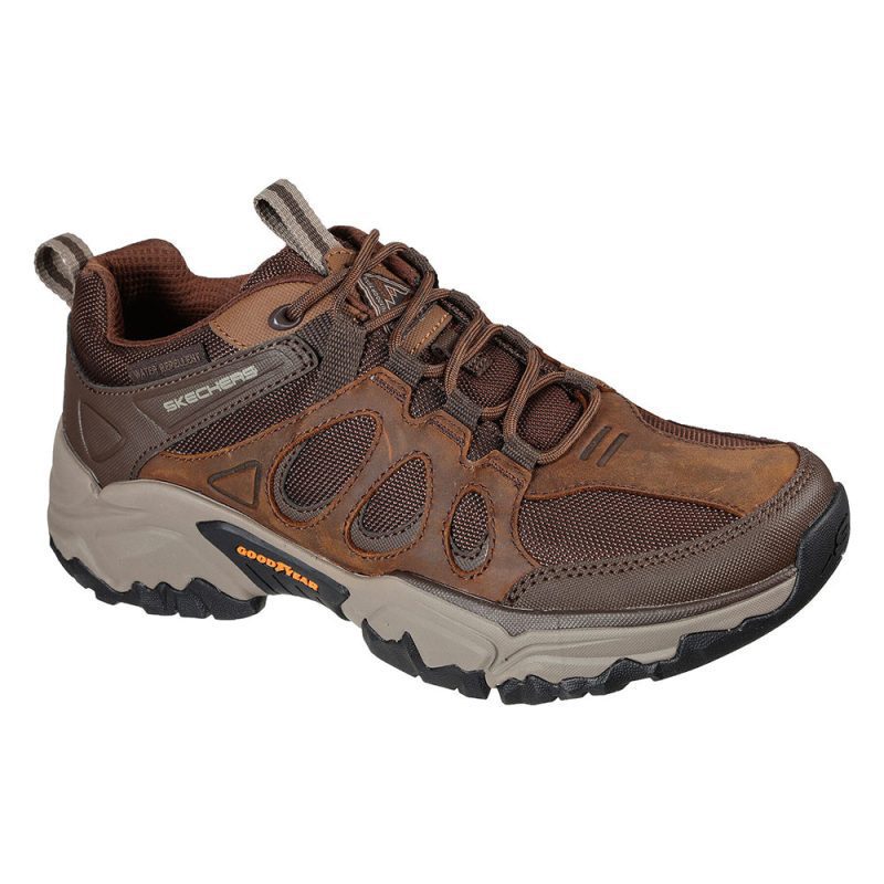 A brown and gray Skechers SKECHERS SELVIN RELAXED FIT DARK BROWN - MENS with a rugged sole, breathable mesh panels, and multiple laces. The athletic shoe features Goodyear Performance Outsole branding on the midsole and Skechers branding on the upper.