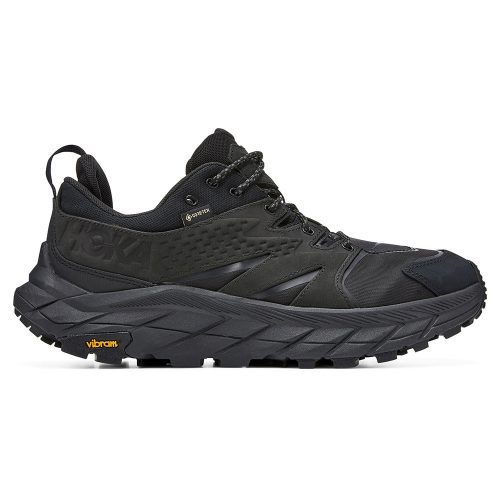 A black HOKA ONE ONE ANACAPA LOW GTX BLACK/BLACK - MENS running shoe with a thick, rugged sole made from Vibram Megagrip rubber, waterproof nubuck leather, lace-up front, and Hoka logo on the side.