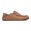 A side view of the Olukai OLUKAI KIPUKA HULU SLIPPER NATURAL/NATURAL - MENS, a single brown leather slip-on shoe with detailed stitching, flat sole, and a casual design featuring nubuck leather accents.