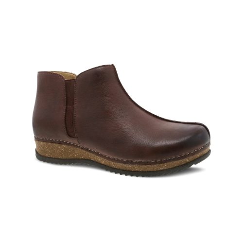 The Dansko Makara Brown Waxy - Women's is a single brown leather ankle boot with a low wedge heel and elastic side panel, crafted using waste-reducing methods.