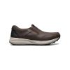 Brown slip-on work shoes with a black sole and white midsole, featuring a leather upper and padded collar for comfort. The Nunn Bush NUNN BUSH EXCURSION MOC TOE SLIP ON CRAZY HORSE BROWN - MENS offer excellent moisture management and are displayed against a plain white background.