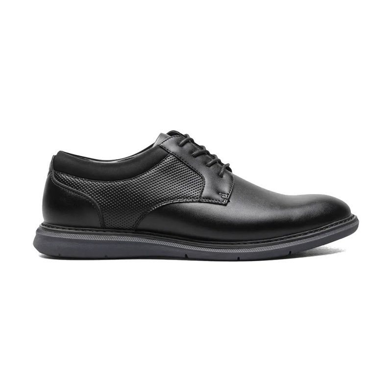 A Nunn Bush NUNN BUSH CHASE PLAIN TOE OXFORD BLACK - MENS with a textured side panel, lace-up front, and a flat rubber sole, viewed from the side. The versatile shoe features a cushioned footbed for added comfort.