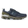 Side view of a navy and olive green athletic shoe with the "On Running" logo on the side, featuring a rugged Missiongrip rubber sole designed for outdoor performance. These ON CLOUDWANDER WATERPROOF MIDNIGHT/OLIVE - MENS from On Running are built for all your outdoor adventures.