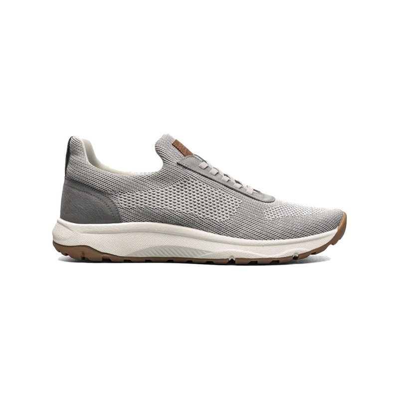 A gray athletic sneaker with a mesh upper, white midsole, and brown rubber outsole viewed from the side, featuring Flexsole Technology for added flexibility and support is the FLORSHEIM SATELLITE KNIT ELASTIC SLIP ON SNEAKER GRAY - MENS by Florsheim.