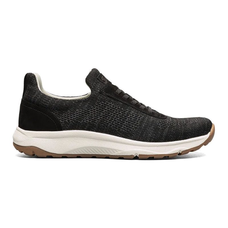 Black athletic dress sneaker with a white midsole and brown, textured outsole. The shoe features a mesh upper, black laces, and innovative Flexsole Technology for ultimate flexibility. Introducing the **FLORSHEIM SATELLITE KNIT ELASTIC LACE SLIP ON SNEAKER BLACK - MENS** by **Florsheim**.