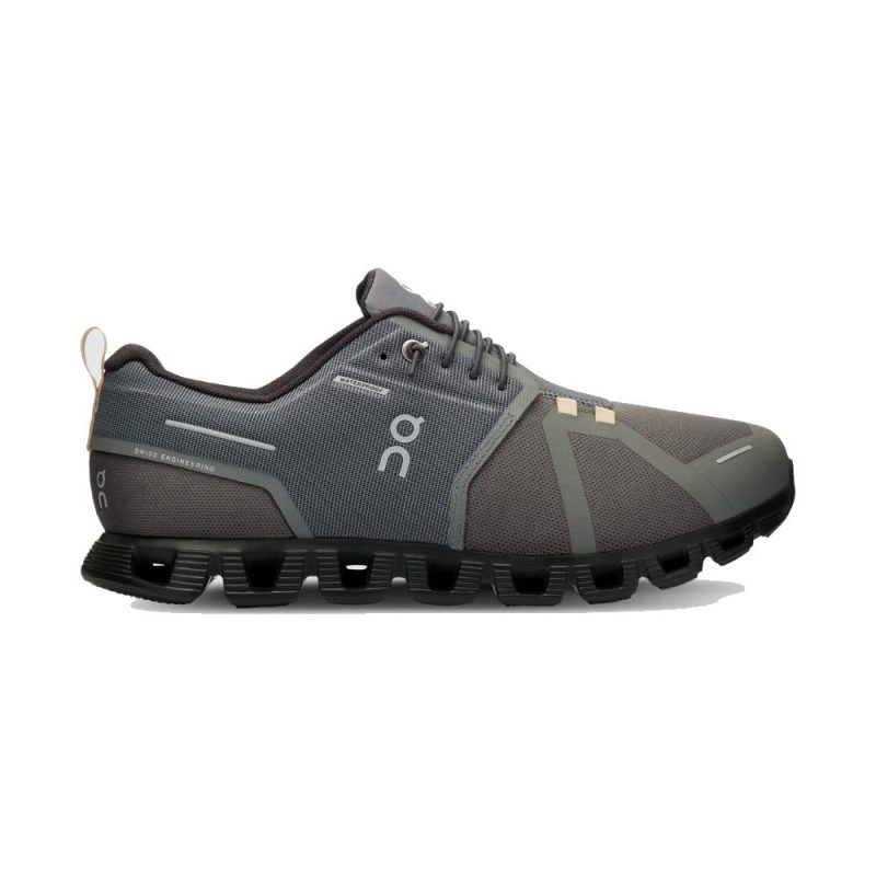 A gray athletic shoe with a unique segmented sole and speed-lacing system, the ON CLOUD 5 WATERPROOF ASPHALT/MAGNET - MENS featuring the On Running logo on the side. It boasts CloudTec cushioning for superior comfort and performance.