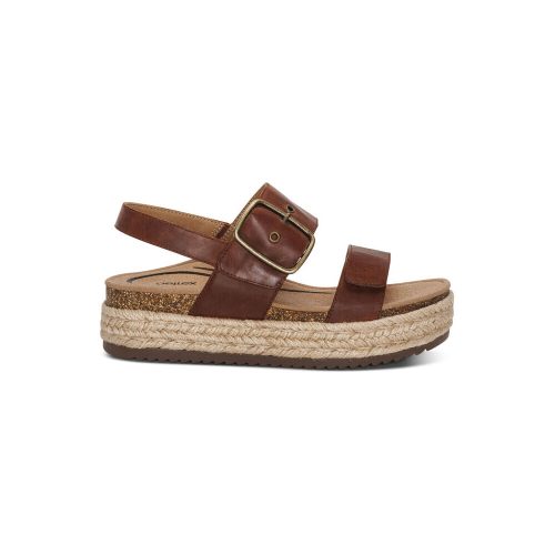 The Aetrex AETREX VANIA WALNUT - WOMENS is a brown genuine leather sandal with a cork footbed, a single adjustable buckled ankle strap, and a braided jute platform sole offering arch support.