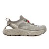 A grey Hoka HOPARA 2 BARLEY/OAT MILK - MENS with a bulky sole, mesh upper, and red lace toggle, crafted using earth-conscious materials.